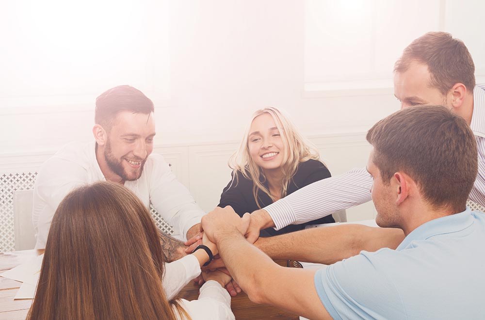 anaheimlighthouse-five-unexpected-benefits-of-sobriety-article-photo-of-team-put-hands-together-show-connection-and-alliance-teambuilding-in-office-young-happy-565007287