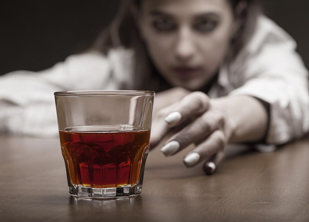 anaheimlighthouse-7-signs-of-alcoholic-denial-article-photo-young-woman-in-depression-drinking-alcohol-on-dark-background-focus-on-the-glass-622570910