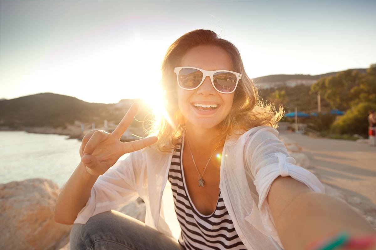 anaheimlighthouse-how-can-i-stay-sober-while-on-vacation-article-photo-beautiful-young-woman-doing-selfie-on-the-beach-302020976