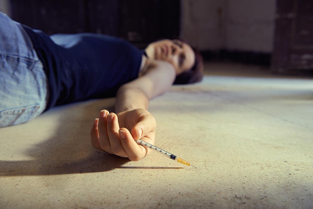 anaheimlighthouse-the-link-between-trauma-and-addiction-article-photo-closeup-of-young-girl-in-heroine-overdose-holding-syringe-and-lying-on-pavement-copy-space