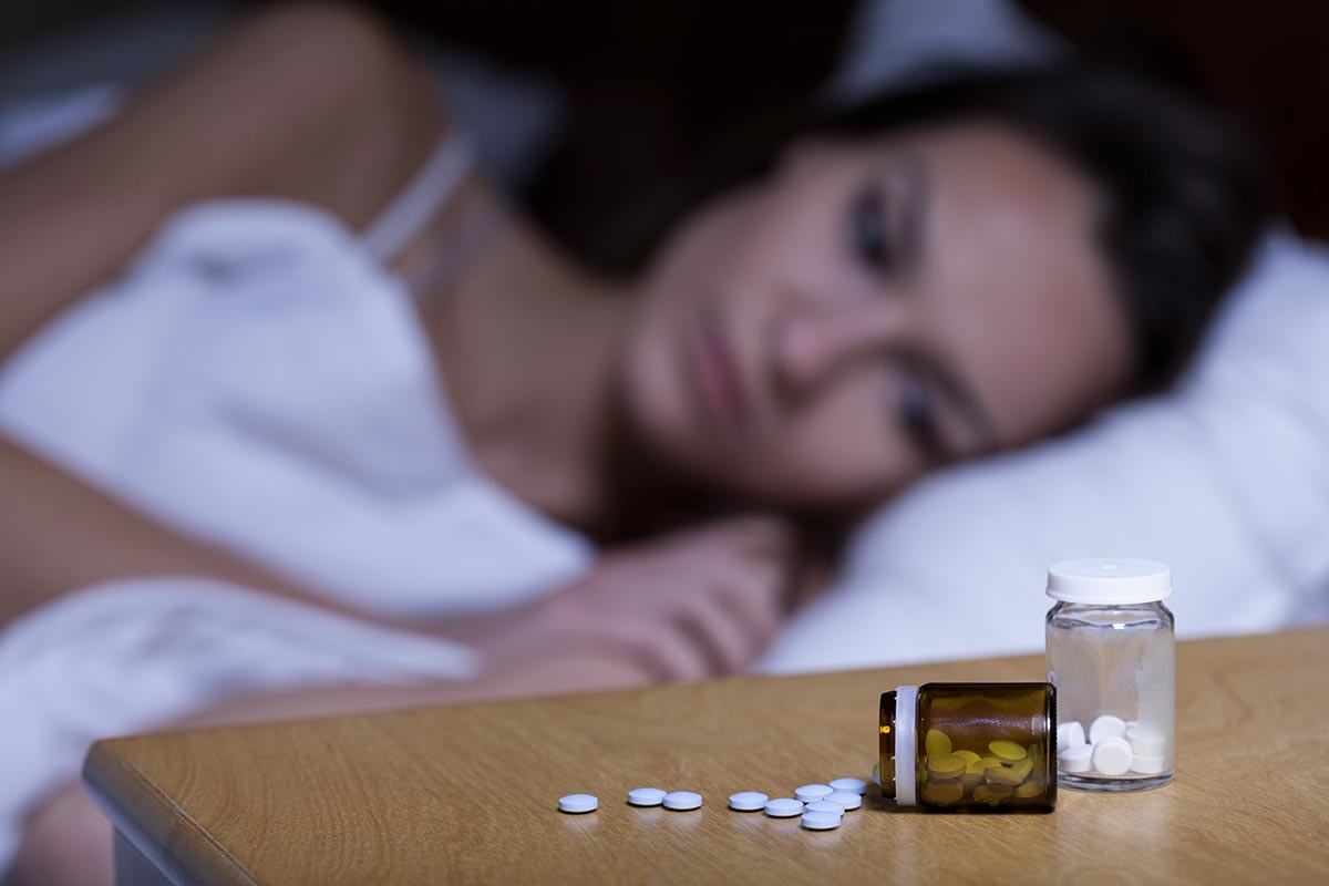 anaheimlighthouse-sleeping-pills-history-use-and-abuse-article-photo-woman-lying-in-bed-taking-sleeping-pills