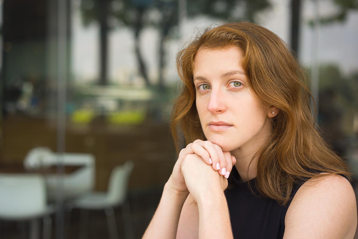 pretty young woman with beautiful brown hair looks sadly into the camera