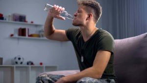Upset Male Soldier Drinking Bottled Alcoholic Drink At Home, Suf