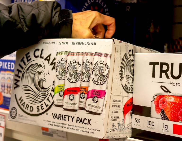 A man grabbing a case of White Claw brand hard seltzer