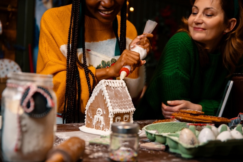 Two women decorating a gingerbread house