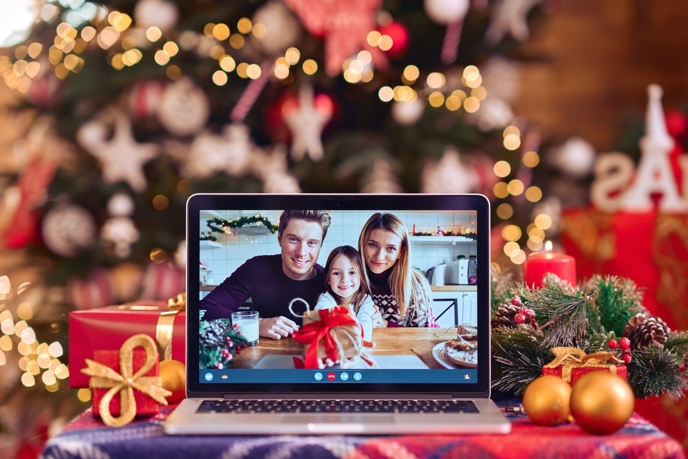 A laptop on a table showing a family video call, with a Christmas tree in the background