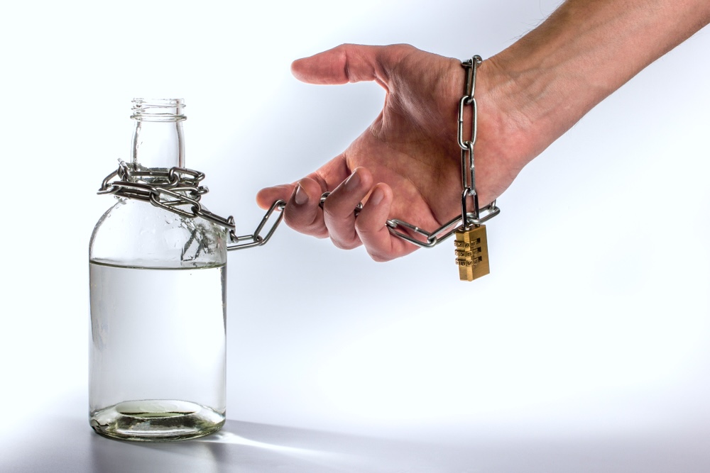 Man’s hand chained to a bottle of alcohol