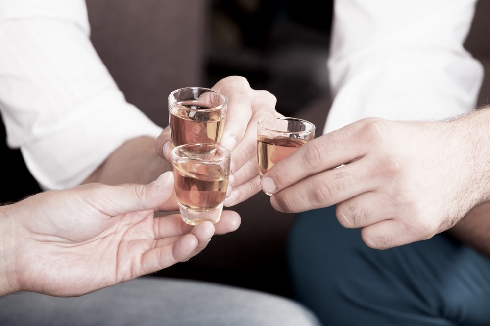 Three people toasting with shot glasses of tequila