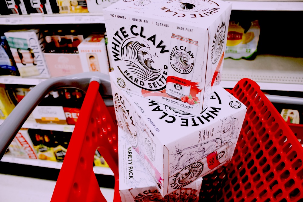 Boxes of White Claw hard seltzer stacked inside a red supermarket trolley