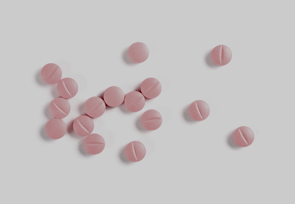 Pink pills scattered on a white surface 