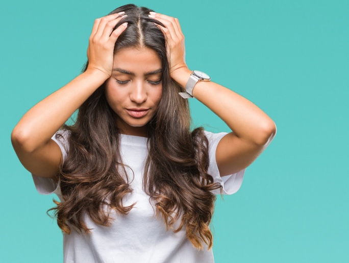 Female struggling with ADHD and depression holding her head with her hands