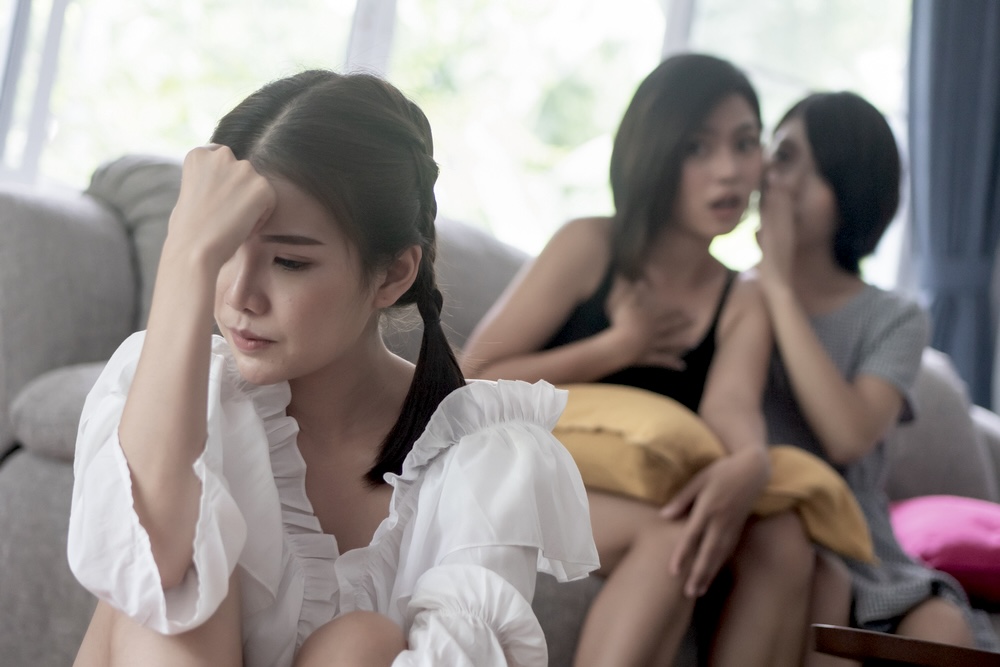 Young woman being gossipped about by her so-called friends