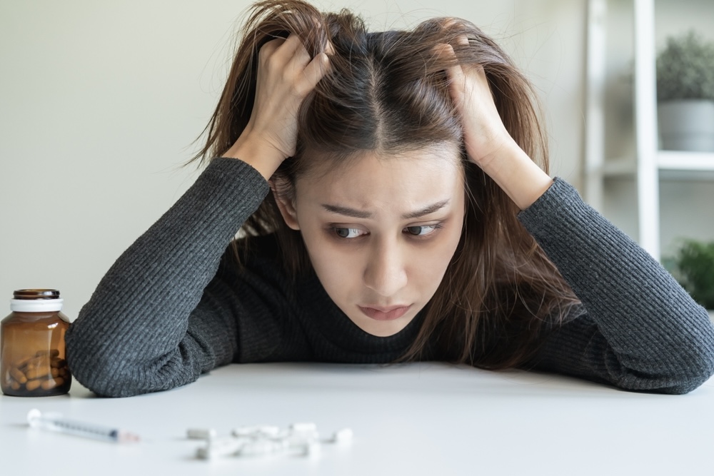 Woman frustrated looking at pills while having drug cravings