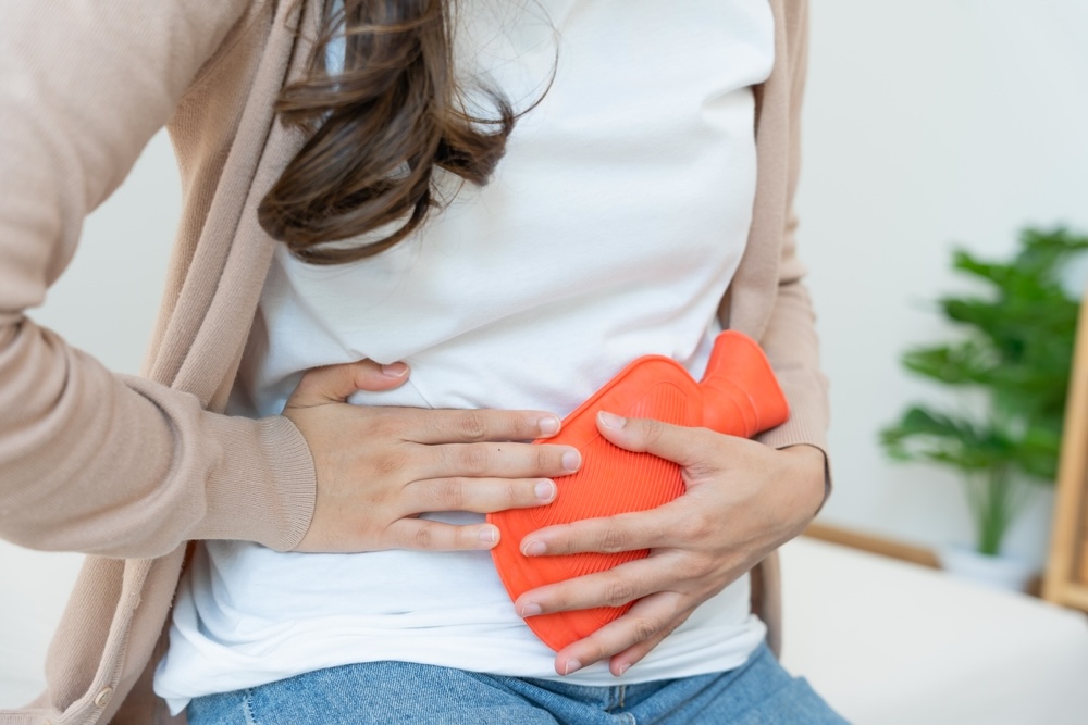 Woman using a hot compress to manage menstrual cramps