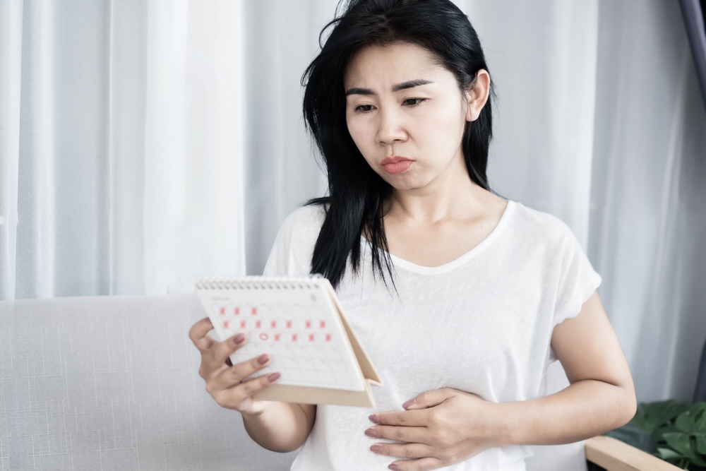 Female holding a calendar looking at her menstrual schedule