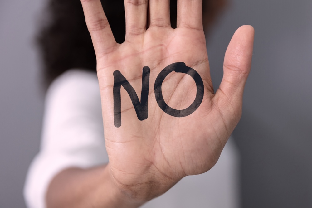 Woman holds up a hand with the word NO written on her palm