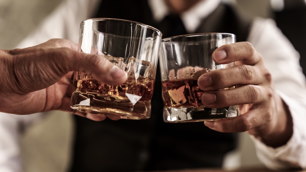 Two corporate men clinking glasses of whiskey