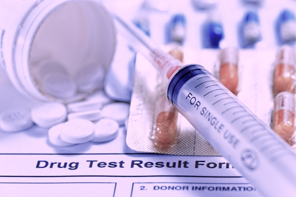 Syringe and different medications scattered on top of drug test result document