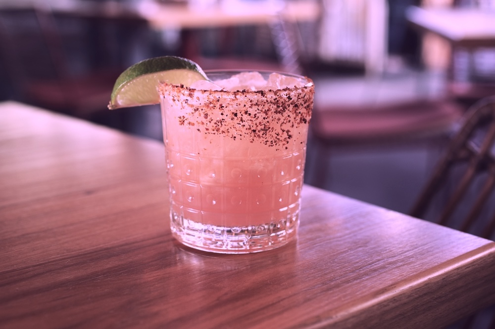 A view of a pink tequila cocktail on the table corner, in a restaurant setting