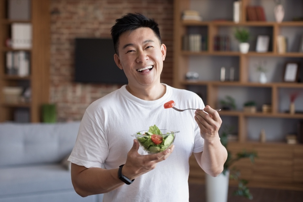 Man in addiction recovery eating a small bowl of salad 