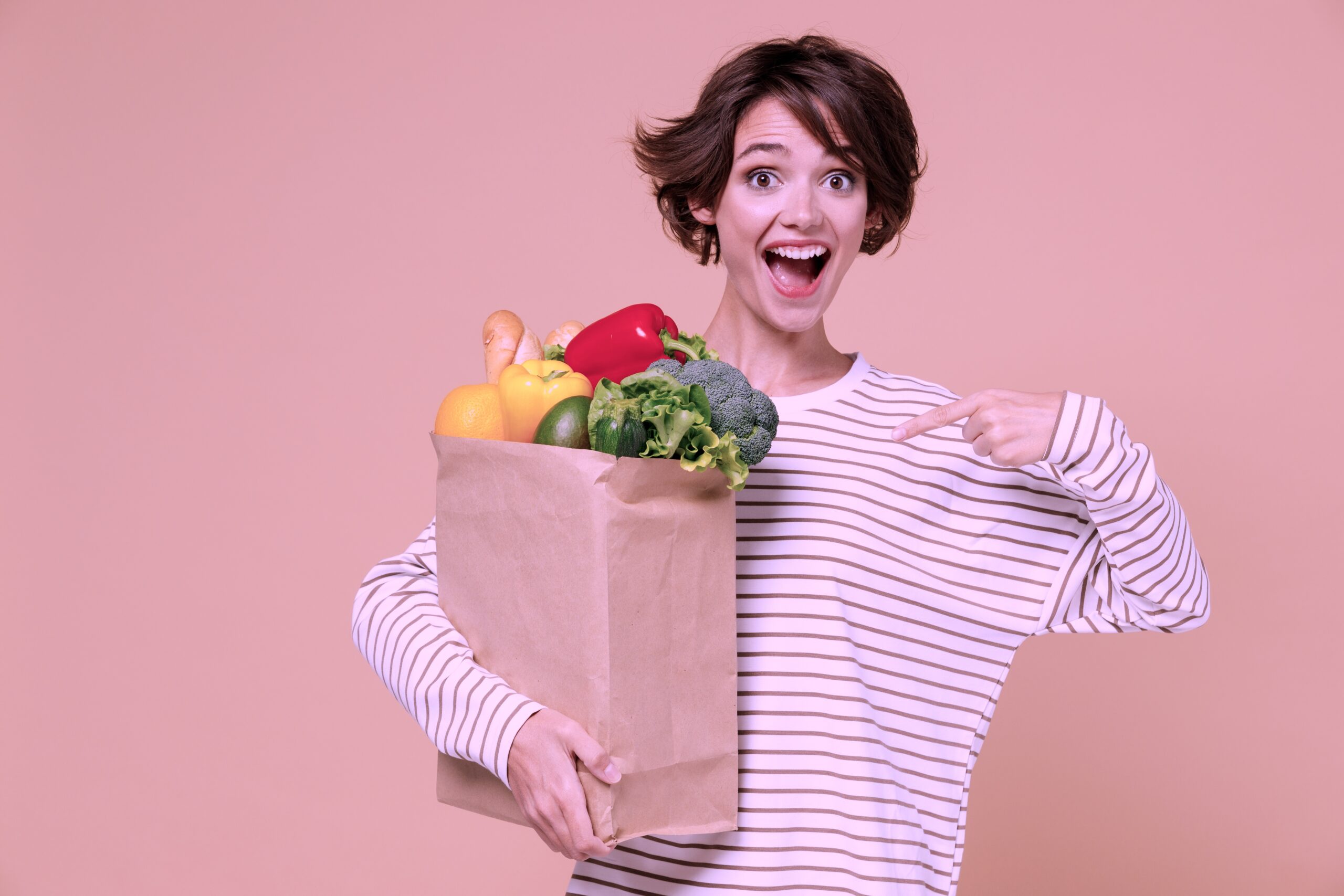 Woman holding a paper brown bag of fresh produce