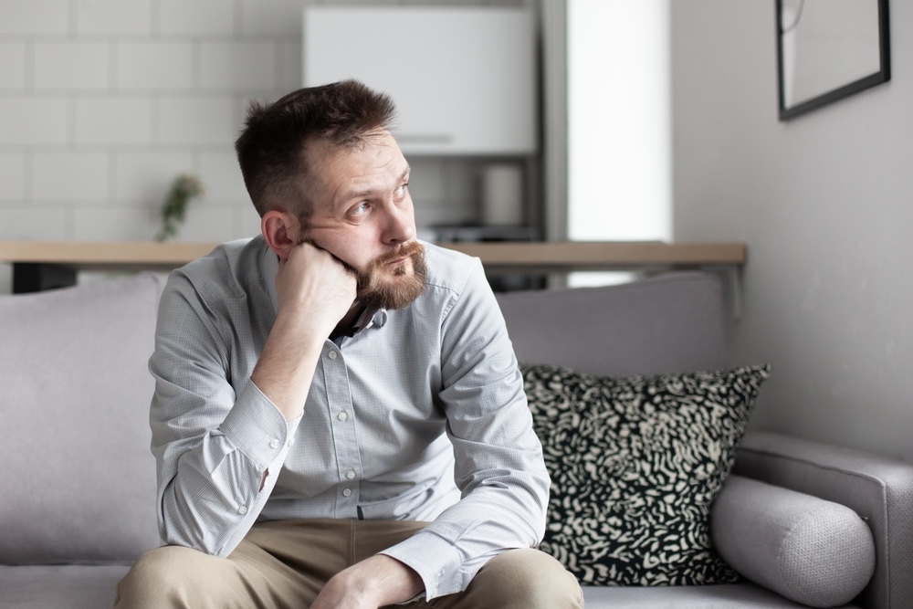 Man with addiction problem sitting on the couch looking outside