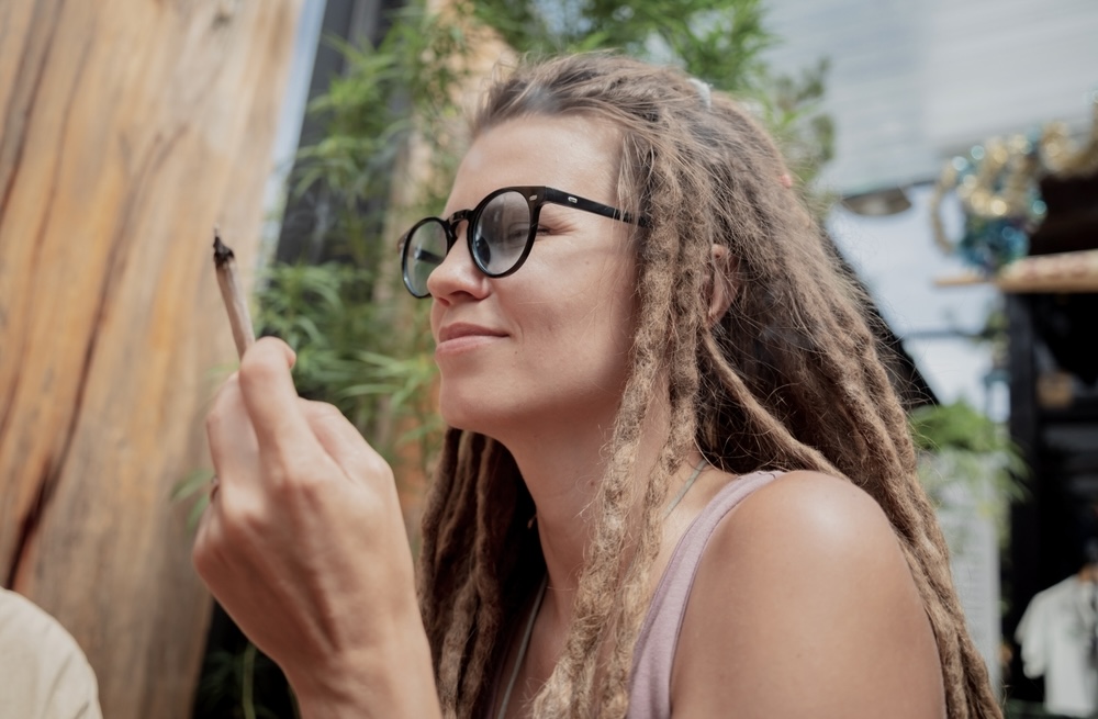 Woman with braids holding a weed joint