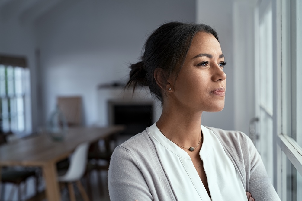 Woman looking out of a window remembering a lost loved one in addiction