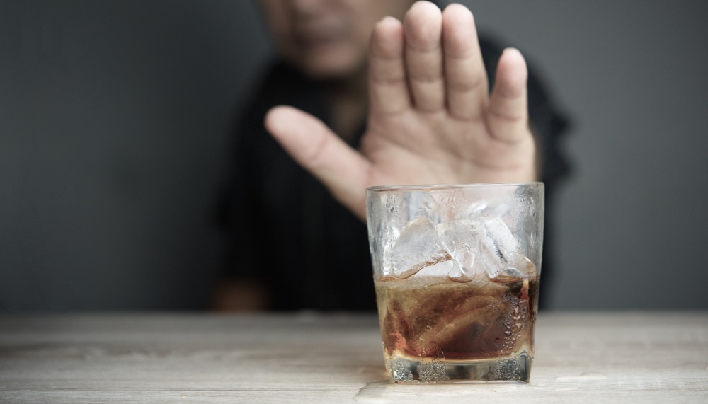 Man refusing an alcoholic drink being offered to him by showing his palm 