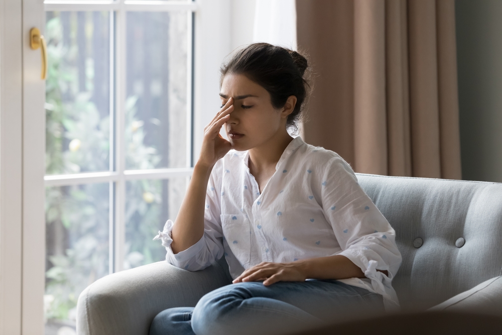 Woman on the couch looking frustrated as she struggles to stay committed to sobriety 