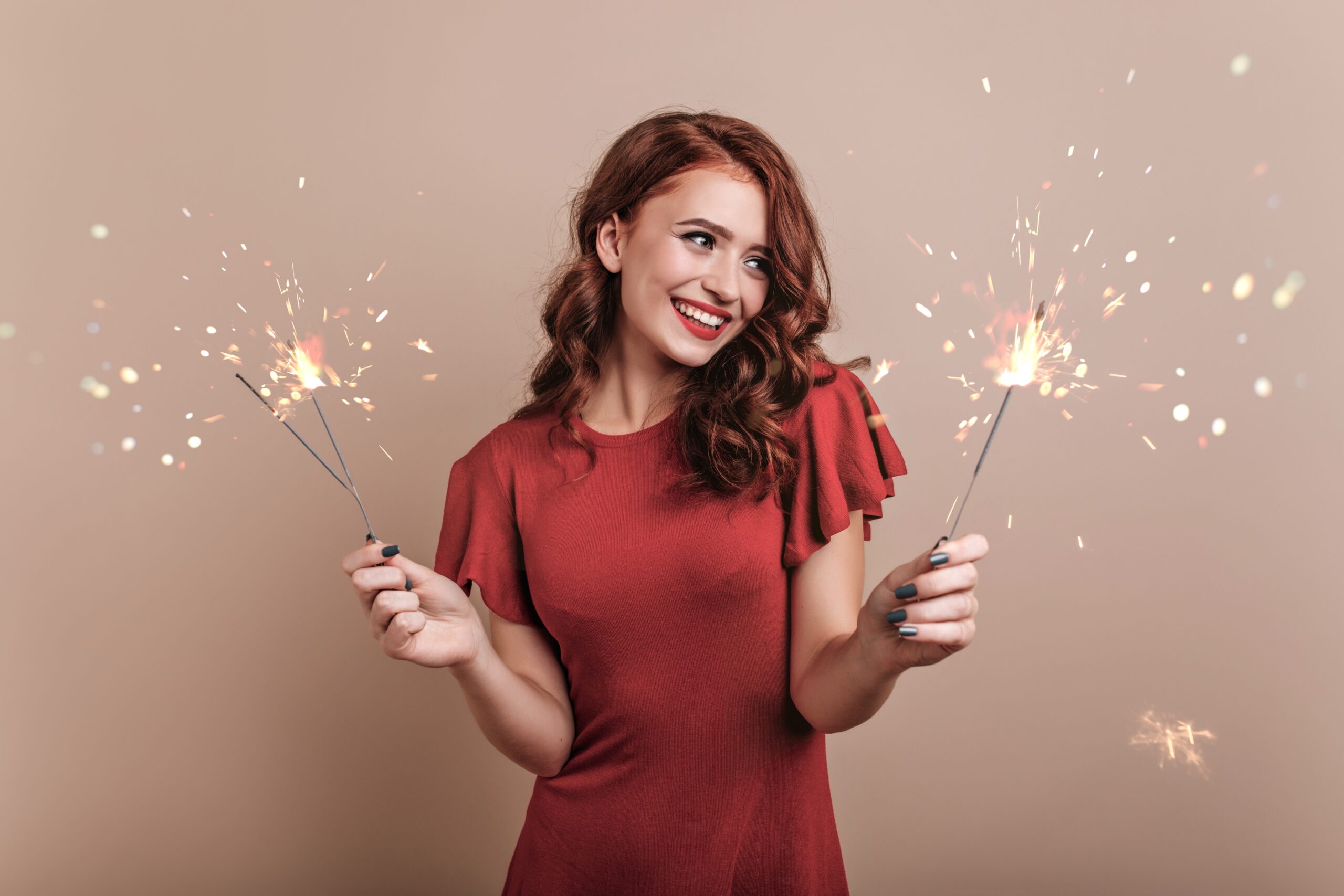 Woman in red dress holding sparklers to celebrate sobriety in the New Year