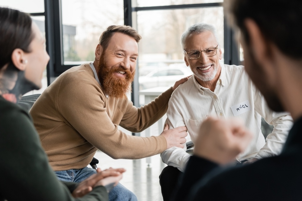 Group of men in addiction recovery meeting congratulating one another