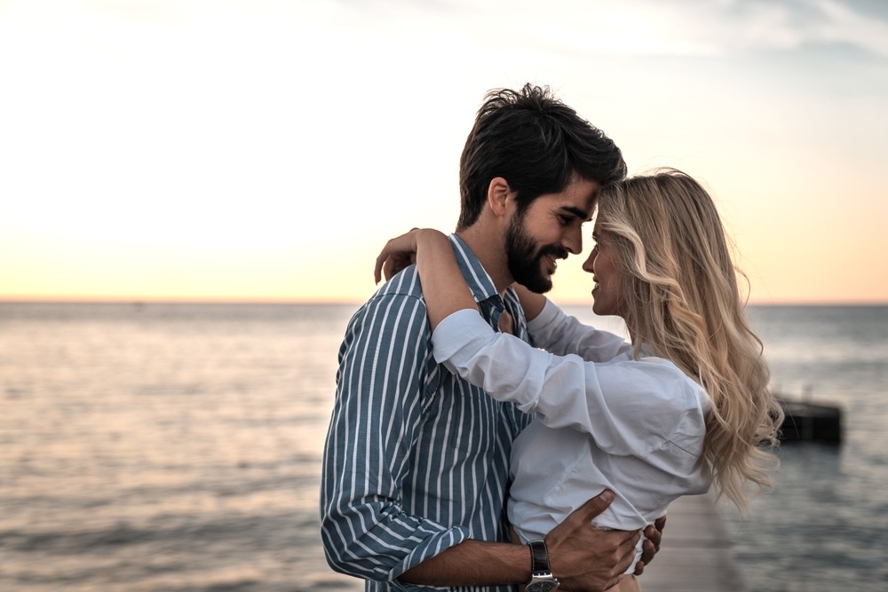 Romantic couple in addiction recovery hugging with the sea in the background