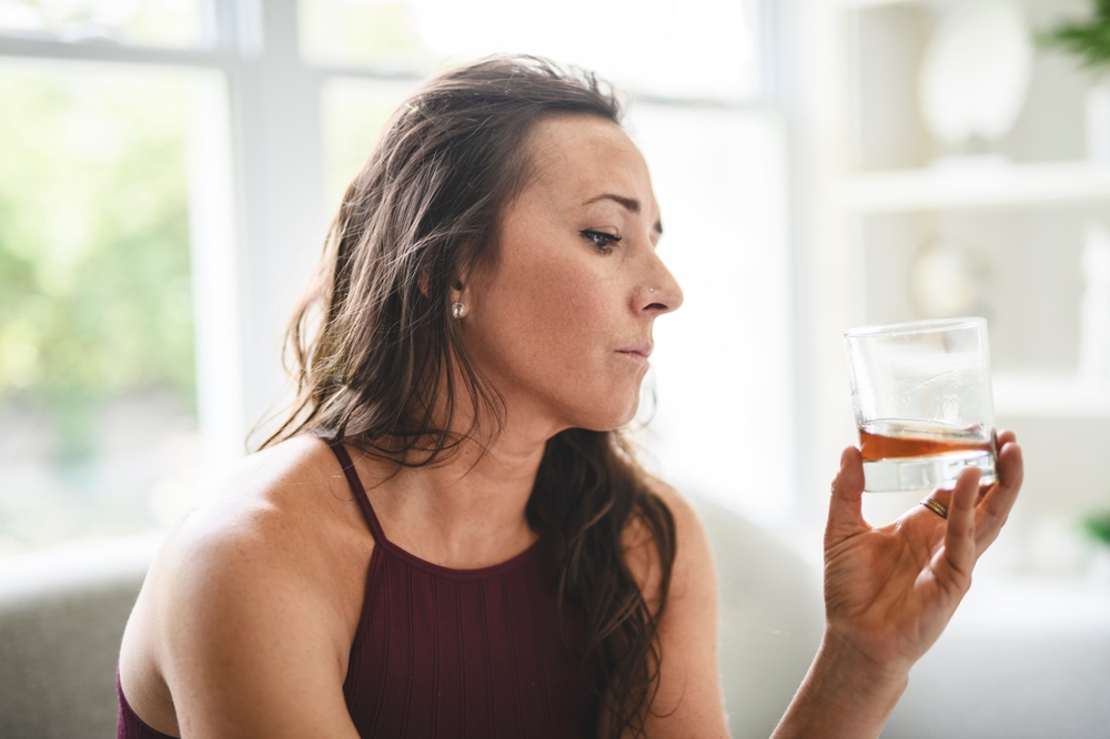 Woman holding a glass of alcoholic beverage wondering if alcohol can help anxiety