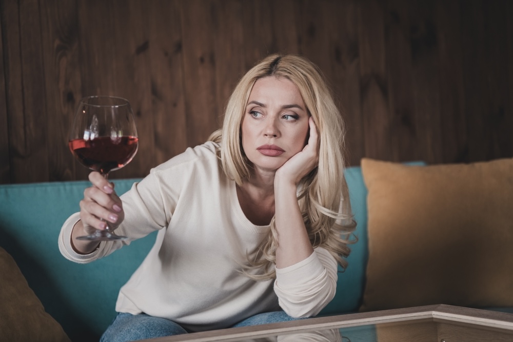 Bored female holding a glass of wine to deal with her emotions